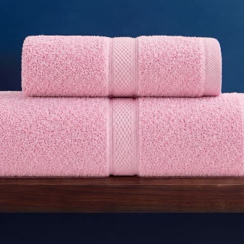 Hai chiếc khăn Toweland màu hồng xếp chồng trên kệ gỗ nền xanh navy.