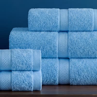 Năm chiếc khăn Toweland màu xanh dương xếp thành hai chồng trên kệ gỗ.